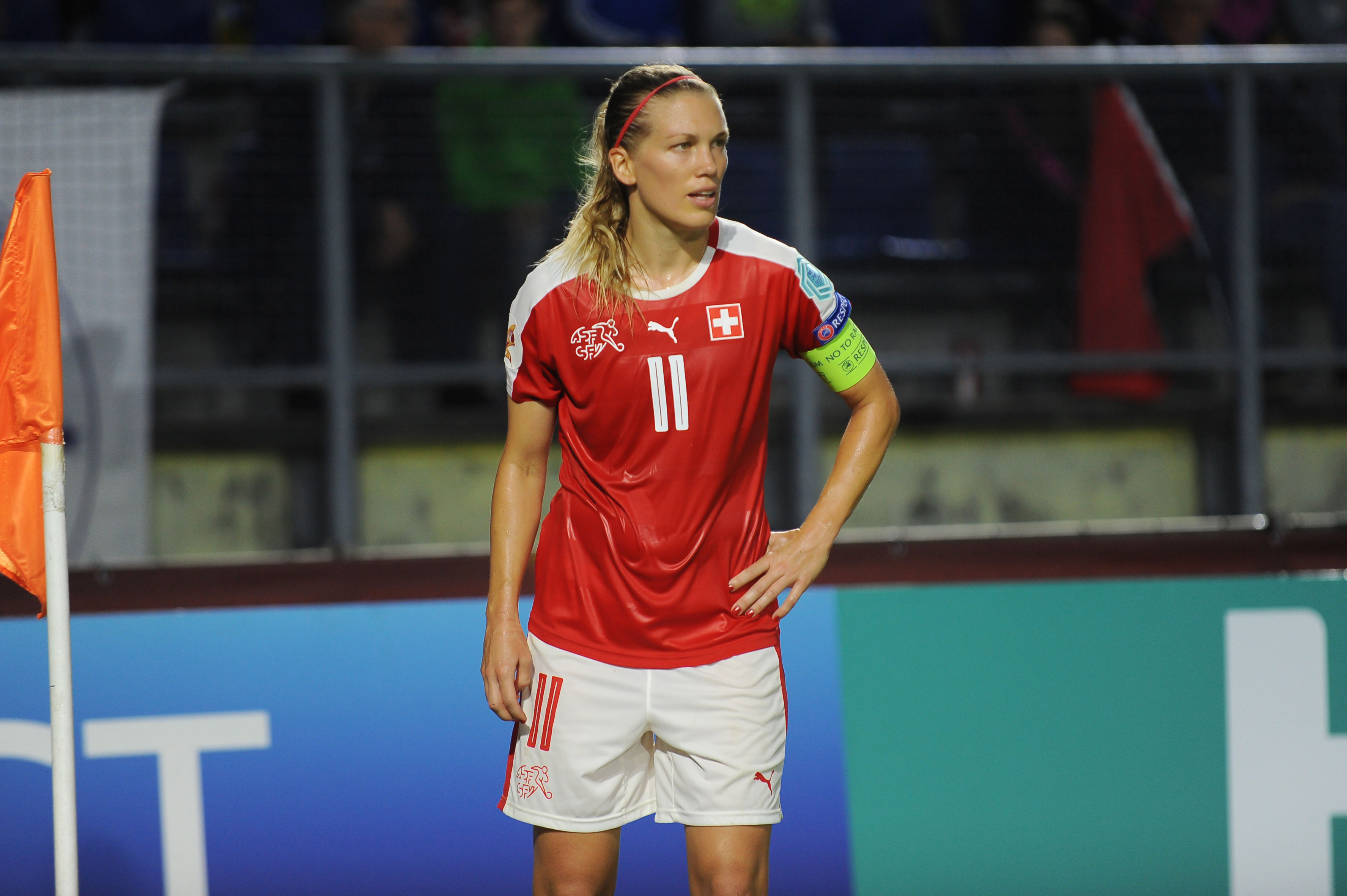 Fussballerin Lara Dickenmann auf dem Fussballplatz schaut nach rechts, Kapitänsbinde am linken Arm.