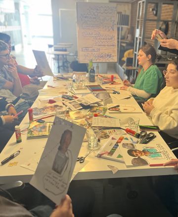 Hier sind Salma und Alessandra am erzählen. Wir sitzen alle am Tisch und sind am überlegen, was wir gestalten könnten.