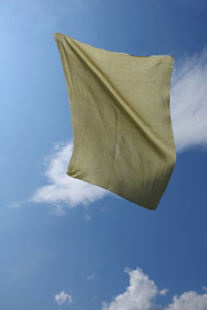 Ein Stück Stoff weht in der Luft. Im Hintergrund blauer Himmel und Wolken.