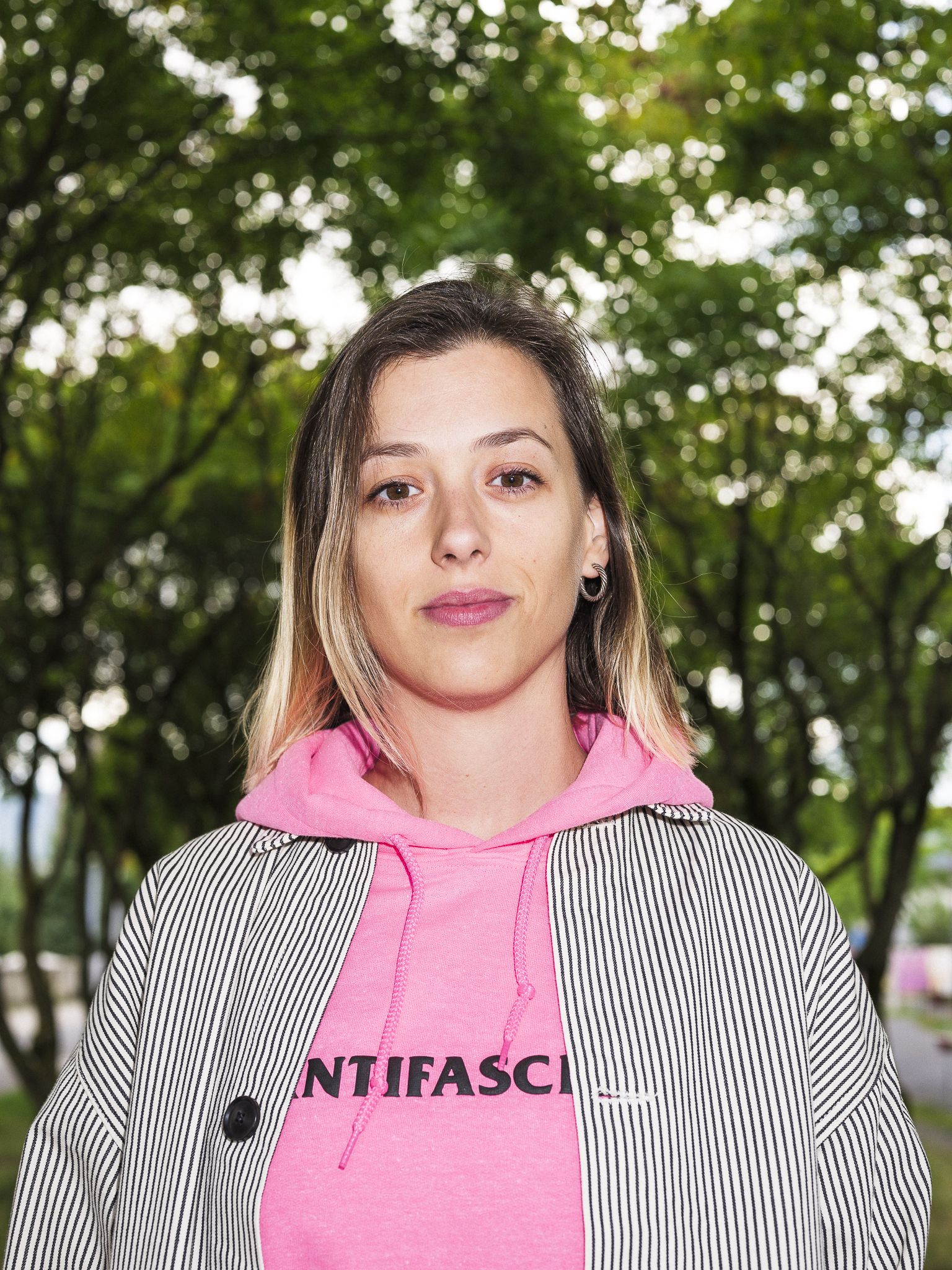 Lisa Christ in einem pinken Pullover vor vielen Bäumen