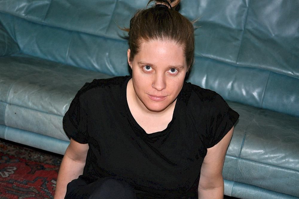 Eine Frau mit schwarzem T-Shirt sitzend vor einem Sofa